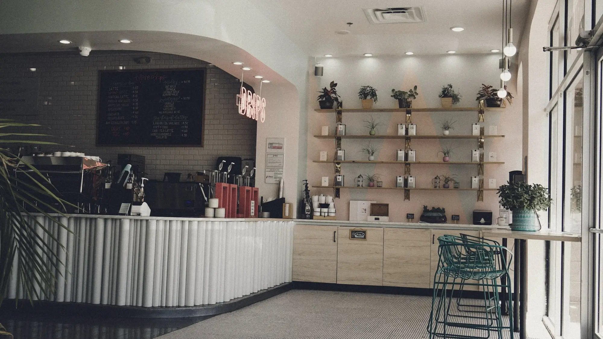 A bright café counter with shelves and stools near the entrance.